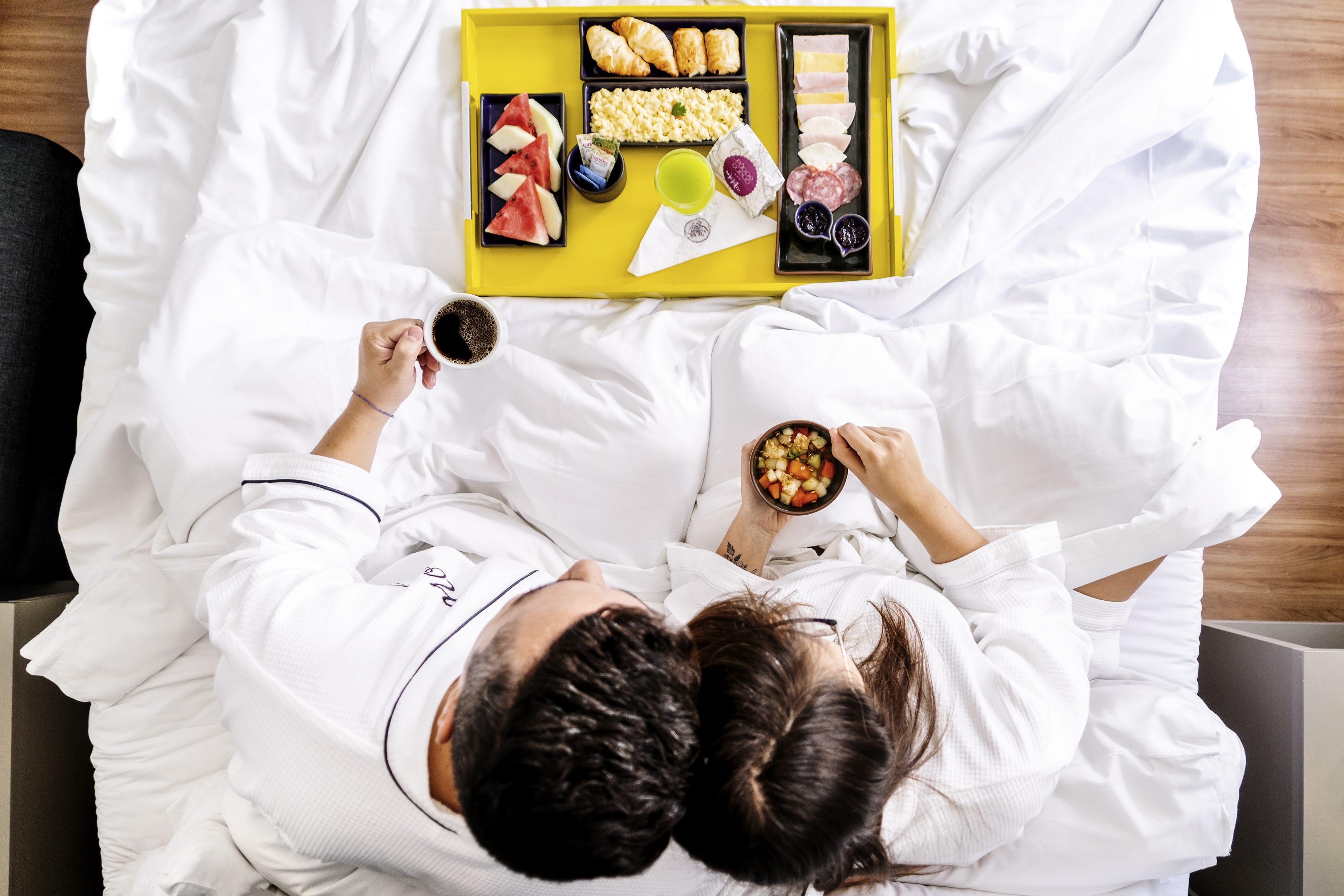 imagem de um casal tomando café da manhã na cama