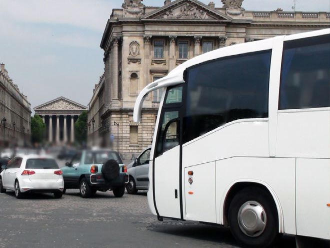 Foto de un autobús blanco, con la Catedral Metropolitana de Buenos Aires al fondo.