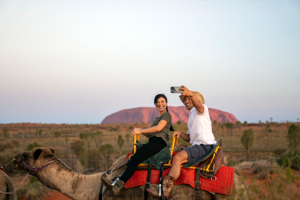 A couple taking a selfie in front of Uluru, an unmissable Australian destination. Visiting Uluru is truly a unique holiday experience, and one well worth putting on your list. Image credit: Tourism NT, Rhett Hammerton