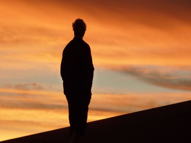 homem sozinho vendo pôr do sol do Atacama