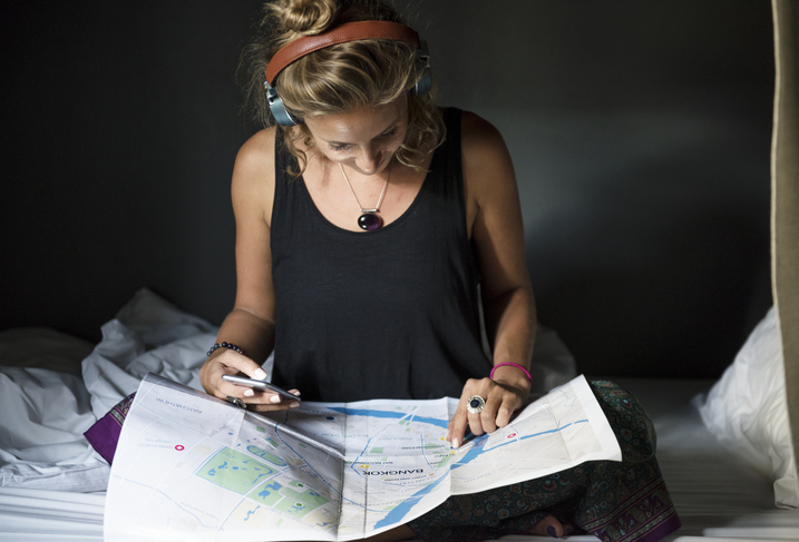 Dicas para viajar sozinha: menina com fone olhando para o mapa.