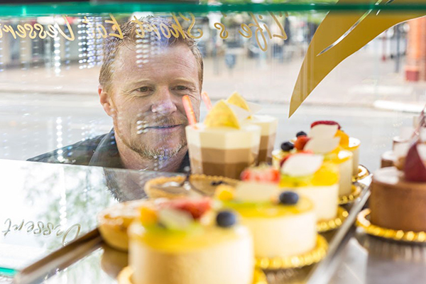A man looking in the window of the Gumnut Patisserie at the delicious cakes, pies, and baked goods. Image credit: Gumnut Patisserie
