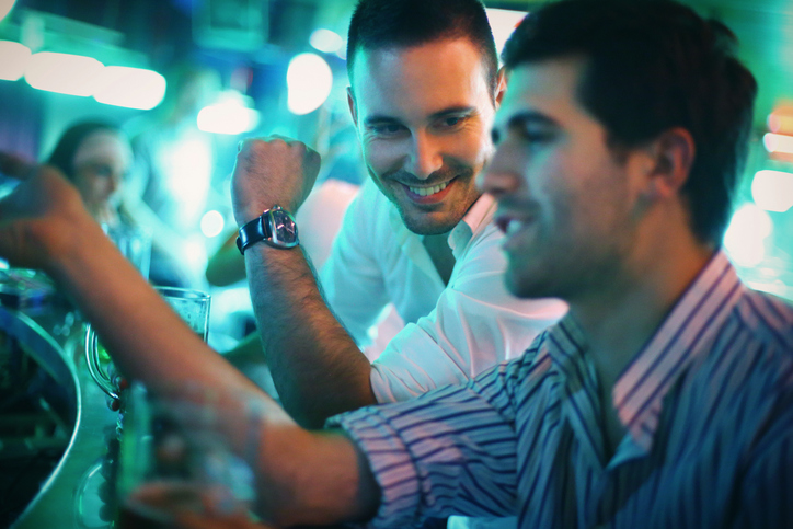 Homens em bar bebendo e sorrindo