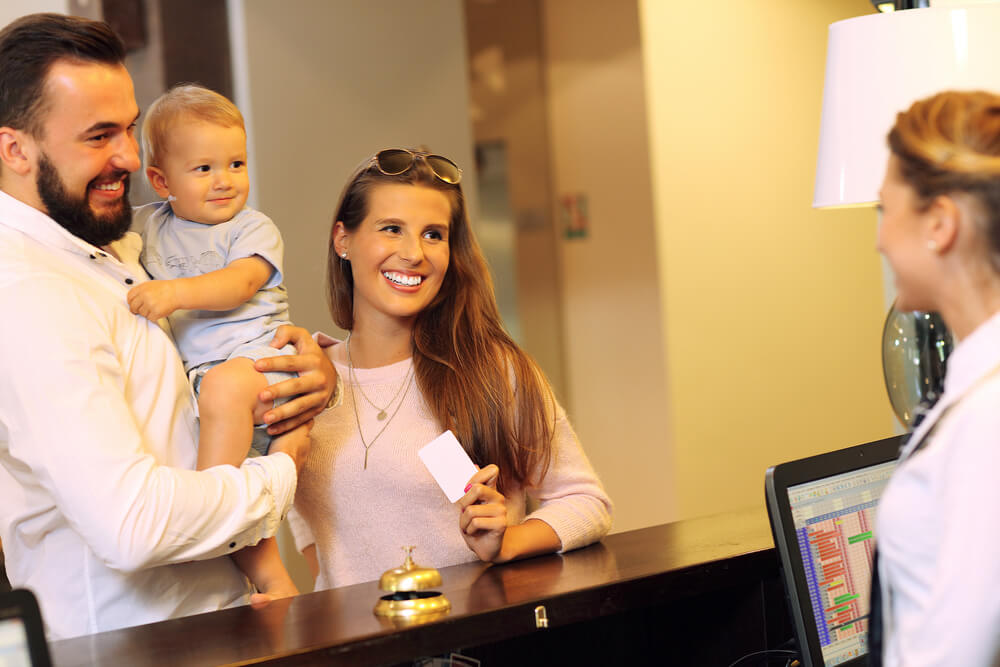 Família de um homem, uma mulher e um bebê fazendo check-in num hotel
