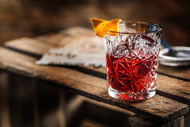 Cocktail Negroni on a old wooden board. Drink with gin, campari martini rosso and orange