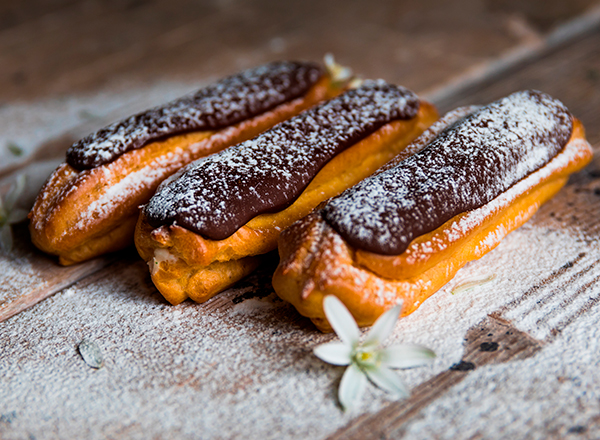 Traditional French dessert. Eclair with chocolate icing in powdered sugar
