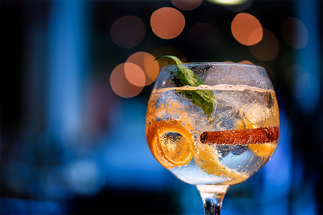 Beautiful glass of gin on bar counter with blurred background in shades of blue and boke