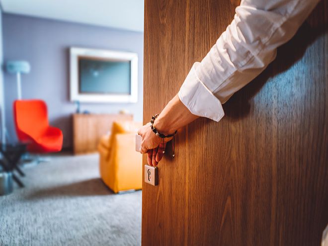 Foto de un brazo abriendo la puerta de una habitación de hotel.