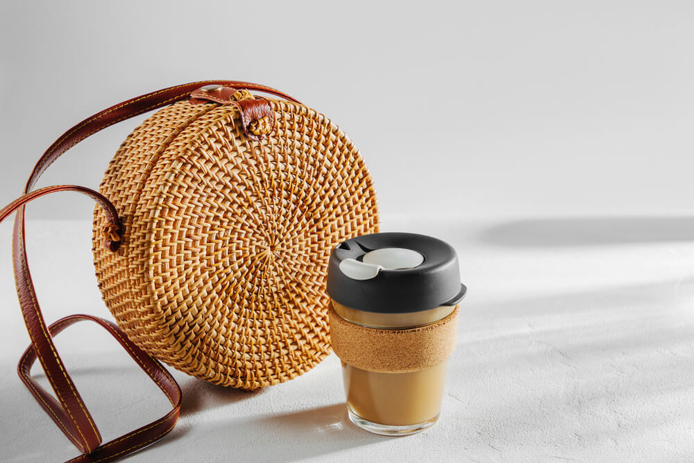 Bolsa de palha com um copo de café sobre mesa