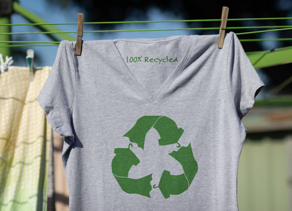 camiseta cinza com logo da reciclagem pendurada em um varal