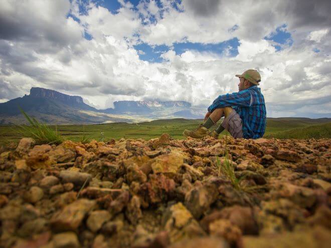 Monte Roraima ao longe avistado por homem sentado na terra lá na Venezuela