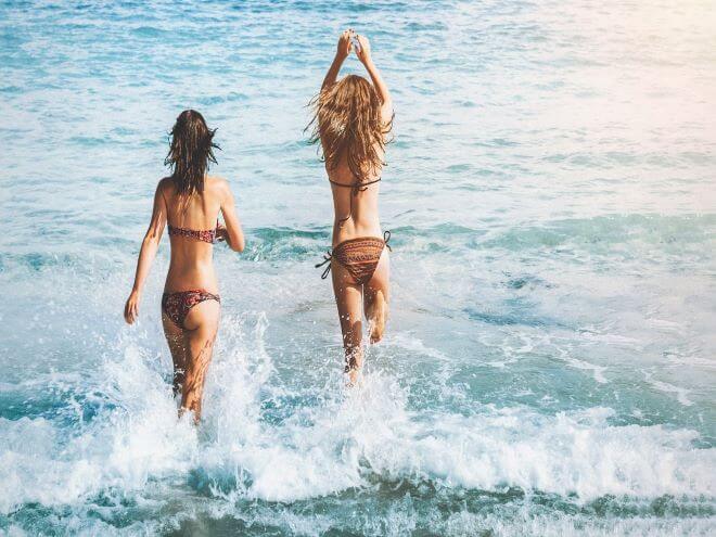 Duas mulheres de biquini  marrom entrando no mar é exemplo de foto entrando no mar