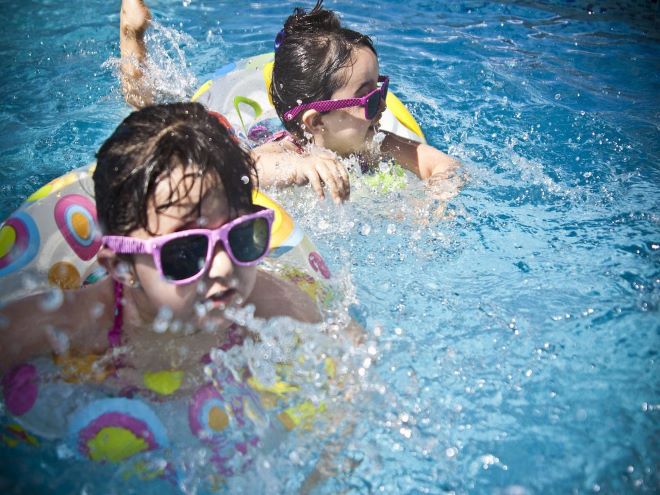 duas crianças pequenas nadando na piscina com boias