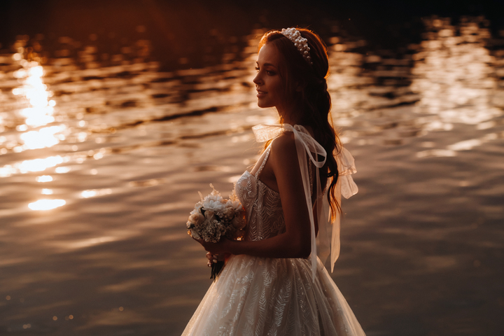 Noiva com buquê perto de uma lagoa pousando para foto