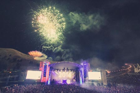 Night Time shot w/ purple stage with green fireworks overhead