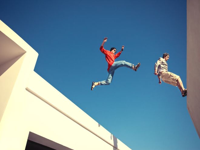 homens saltando de um edifício para o outro em prática de parkour