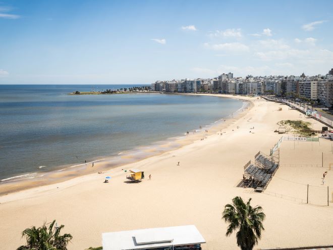 Rambla: praia em Montevideo vista da orla com mar, areia e prédios ao fundo