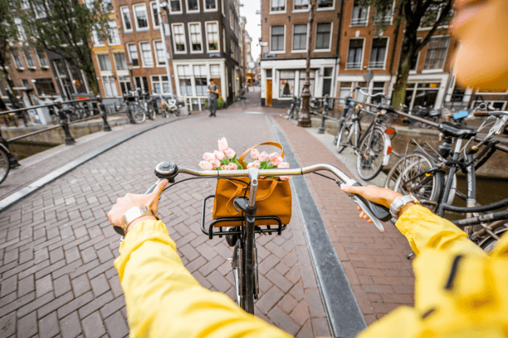 Frau auf einem Fahrrad mit Blumenstrauß auf der Straße in Amsterdam