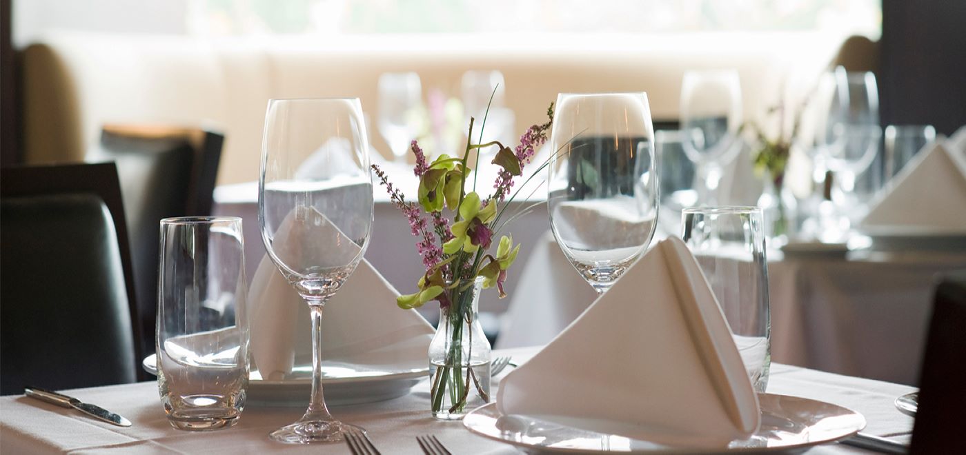 mesa de restaurante decorada com taças, flores e guardanapos