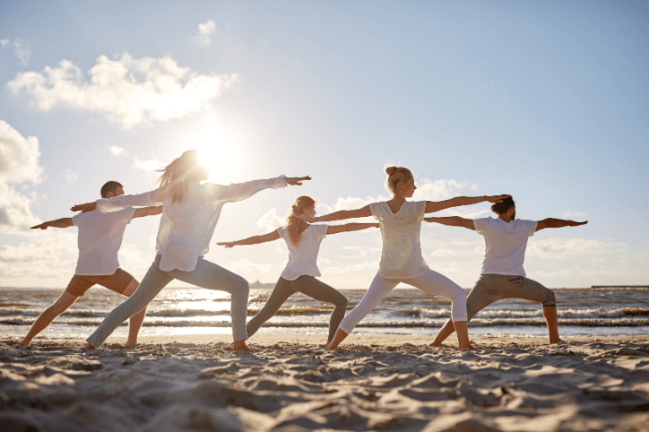 Gruppe von Menschen macht Yoga-Übungen am Strand