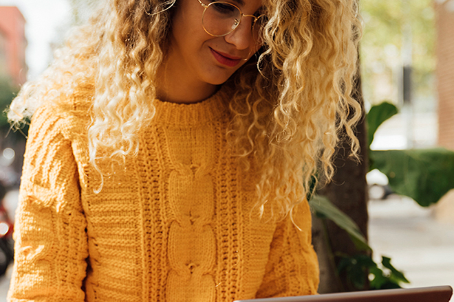 A blonde bespectacled woman in a yellow jumper working with a laptop| ALL – Accor Live Limitless