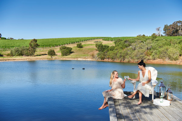 Two people enjoying a glass of wine on holiday in Margaret River. Margaret River is the perfect holiday destination when you want to relax with loved ones and indulge in the finer things. Image credit: Frances Andrijich